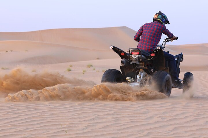 Experience the thrill of navigating the stunning dunes of the Arabian desert on a quad bike connecting with nature and spotting camels in the serene landscape of Dubai.